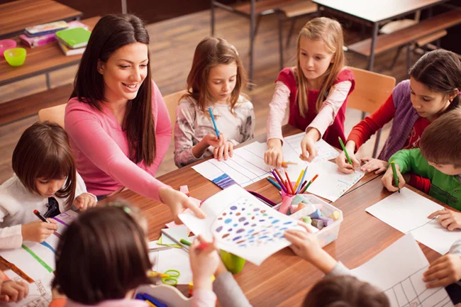 dinamicas para aulas da ebd EBD Hoje - Escola Dominical Dinâmicas para EBD: Veja 20 sugestões de brincadeiras professora sorrindo em uma sala de aula com quatro crianças sorrindo, todas elas concentradas em um livro desenhado que a professora está mostrando. A sala de aula pode ter carteiras, quadro-negro, janelas e decorações temáticas de educação infantil. A professora pode estar apontando para alguma parte do livro enquanto as crianças estão olhando atentamente para as ilustrações. O clima é alegre e descontraído, com uma sensação de aprendizado divertido e envolvente.